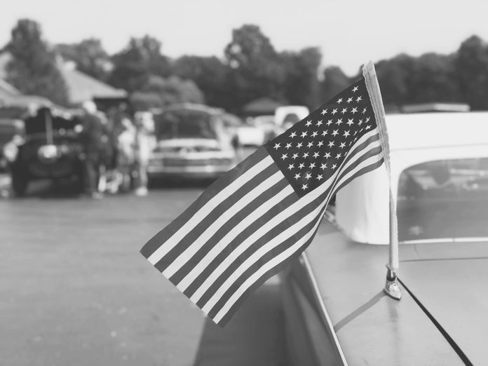 black and white image of an American Flag on an Old Classic Car at a Car Show