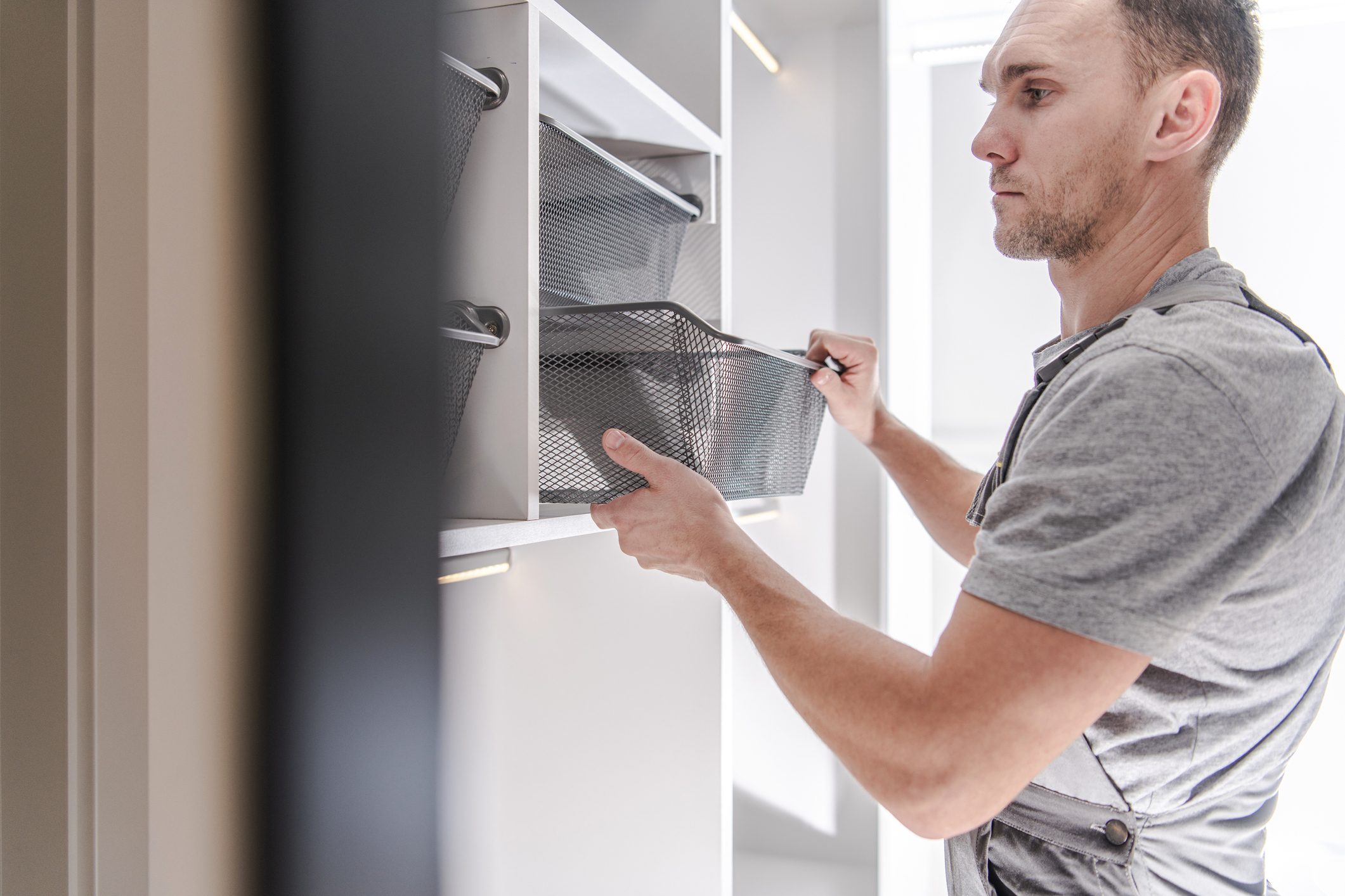 man adding shelves and baskets for organization to a newly remodeled closet