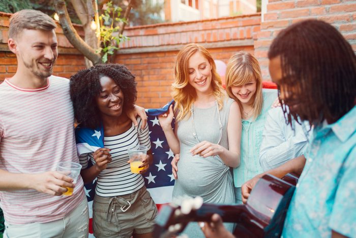 Happy Young People Singing At Backyard 4th of July Party.