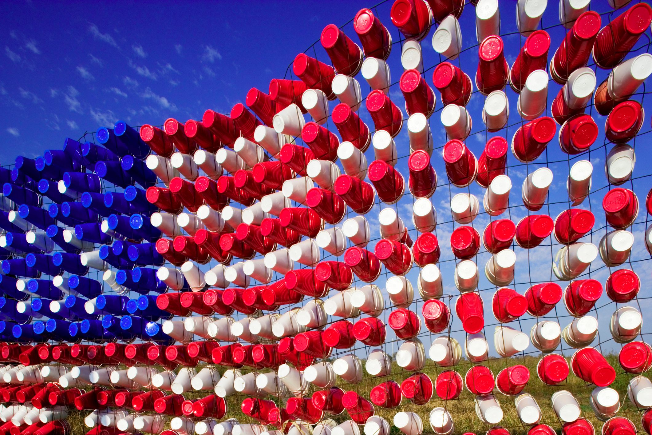 American Flag created out of empty plastic cups stuck in a fence, Leland