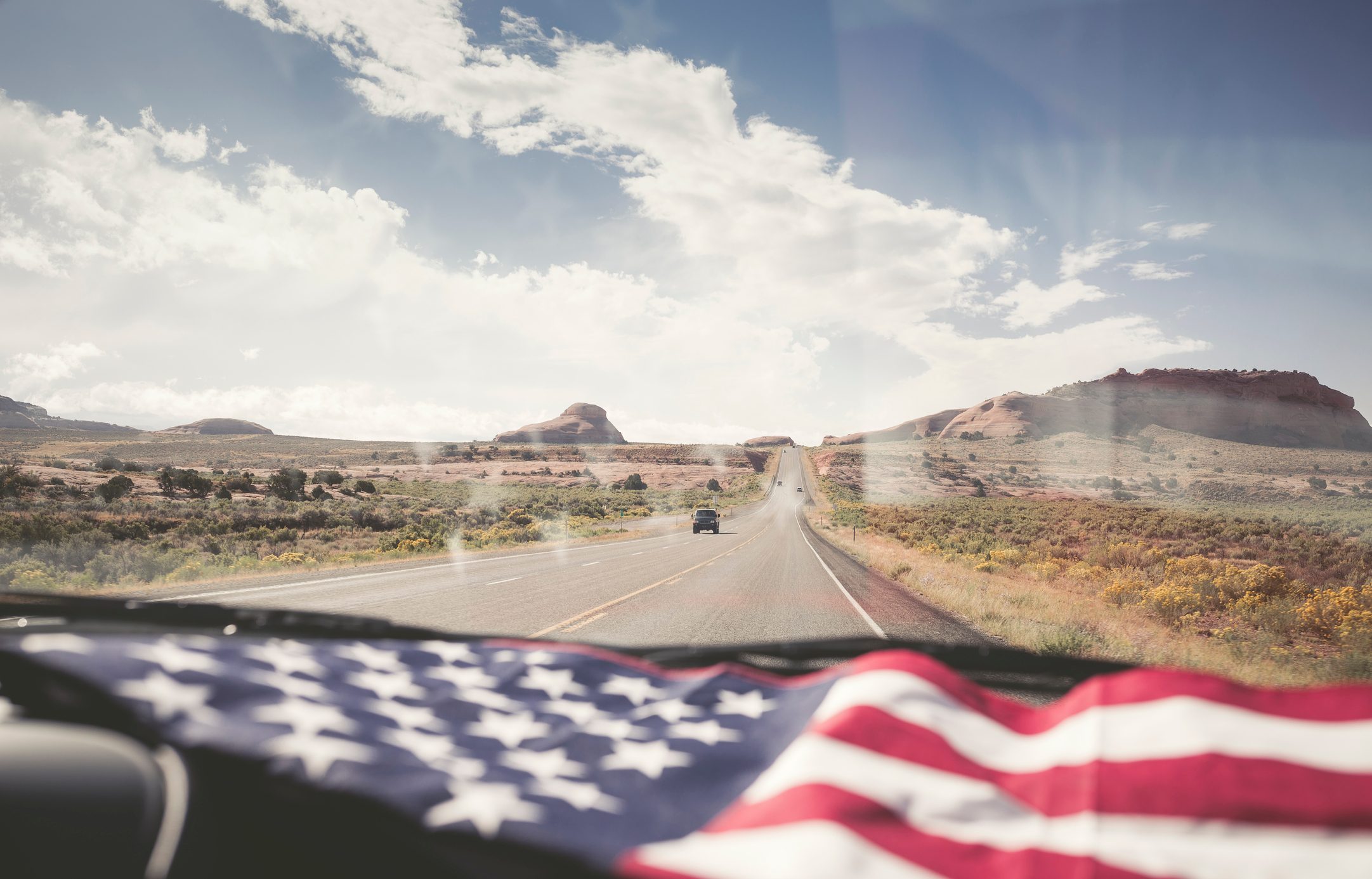 American Flag lying on dashboard of a car on the road in Utah