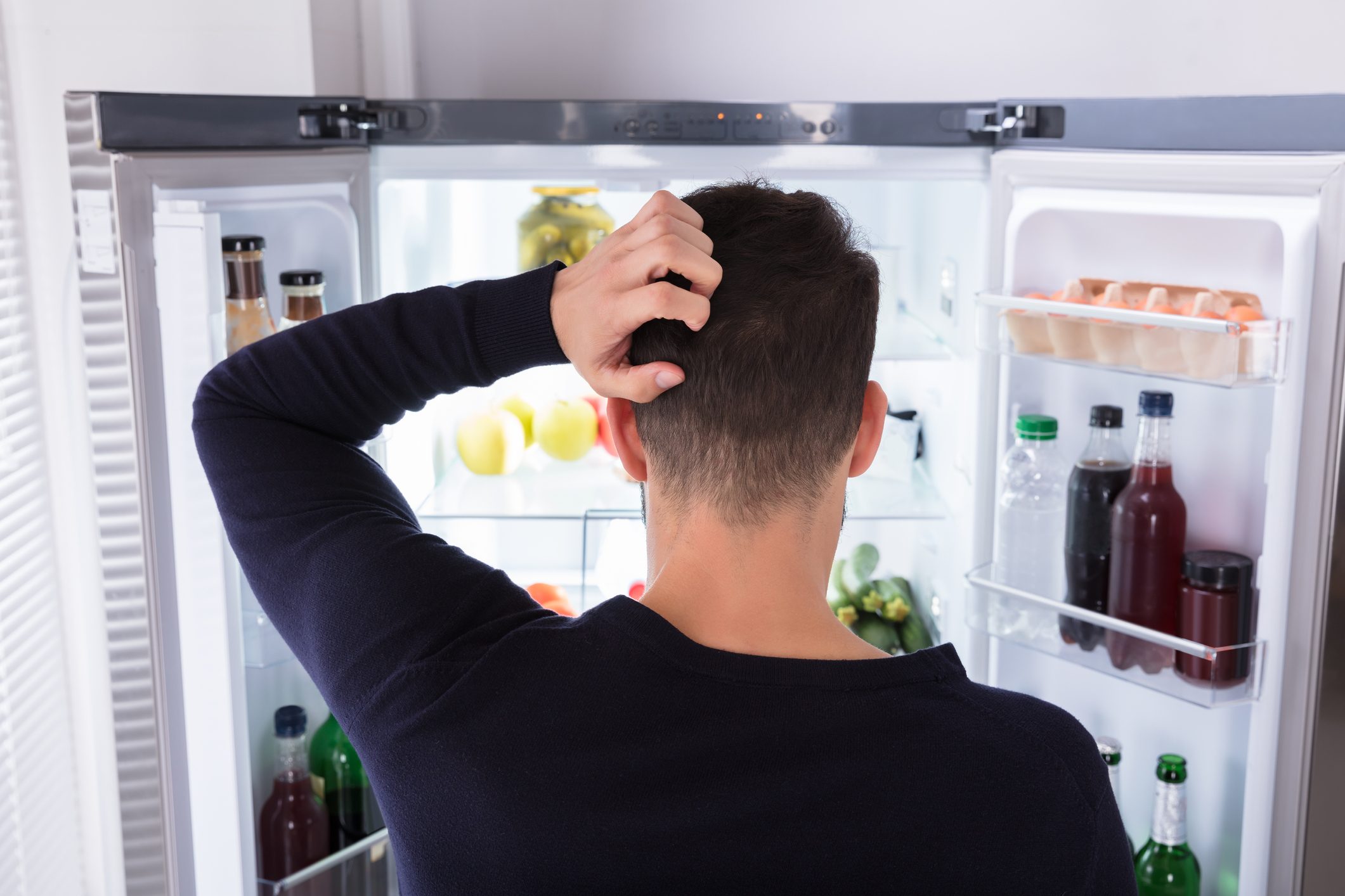Confused Man Looking At Food In Refrigerator