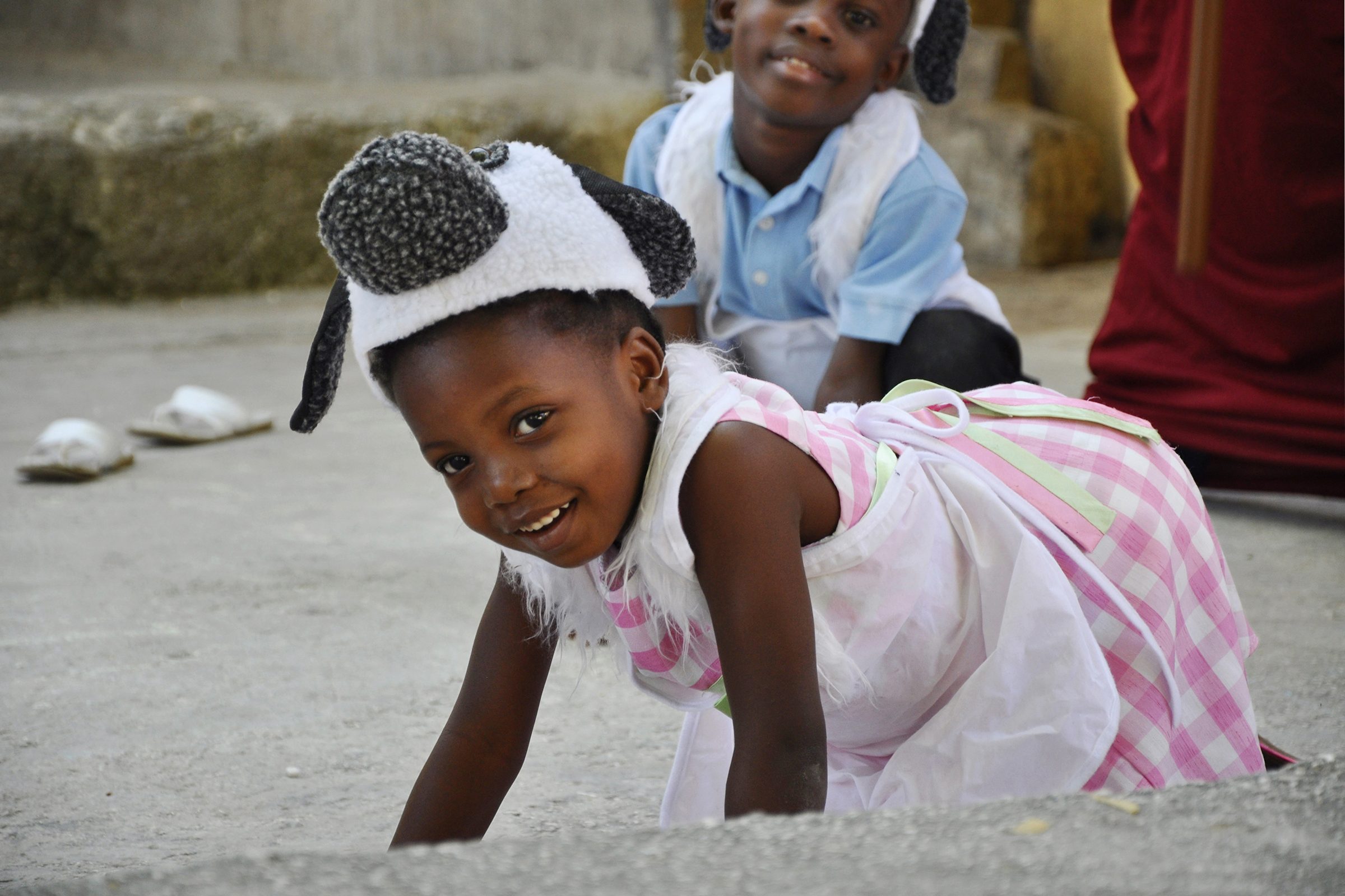 Chika on all fours playing, another child smiles in the background