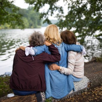 Rear view of women with arms around at lakeshore