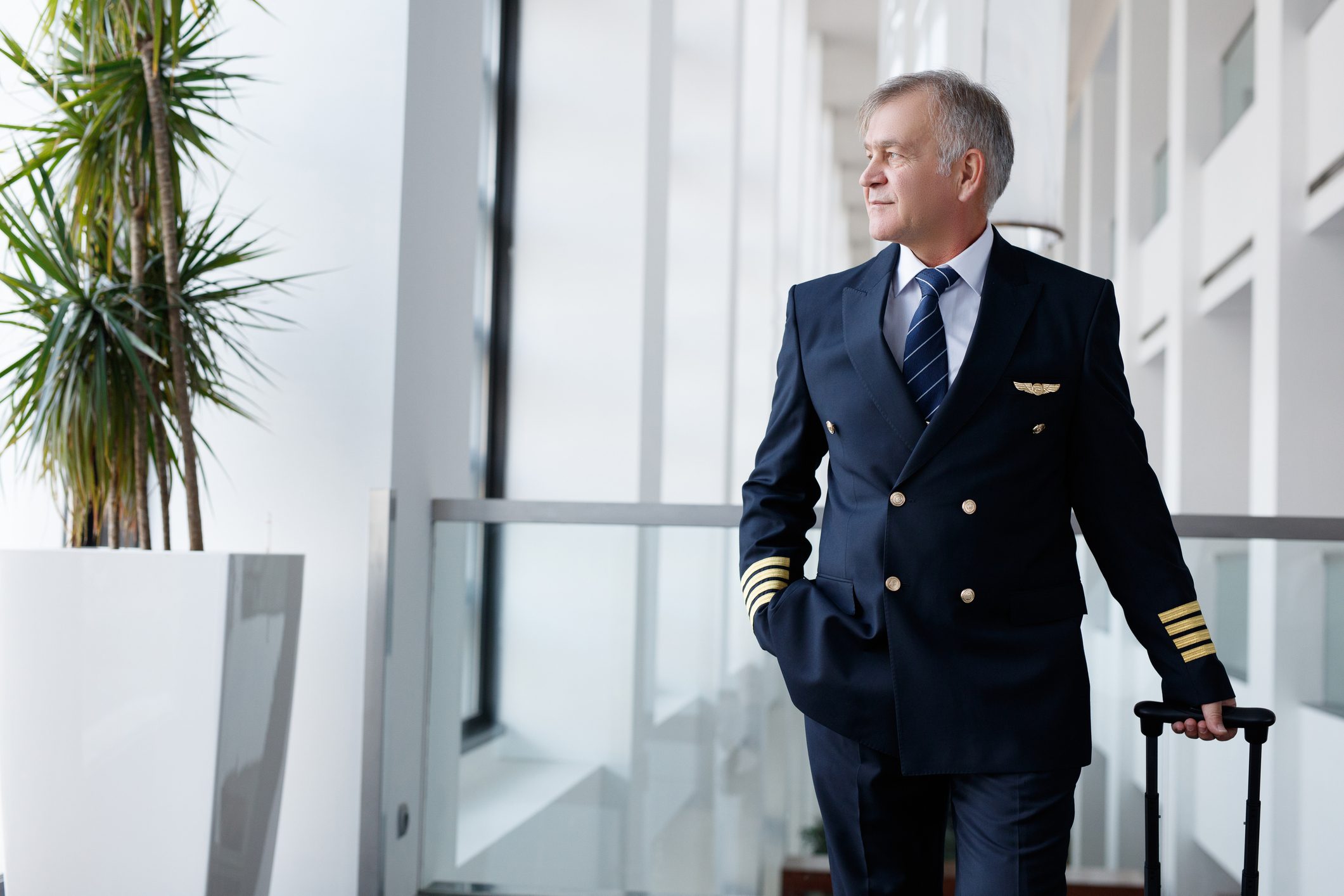 Experienced senior pilot pulling his luggage in the airport terminal