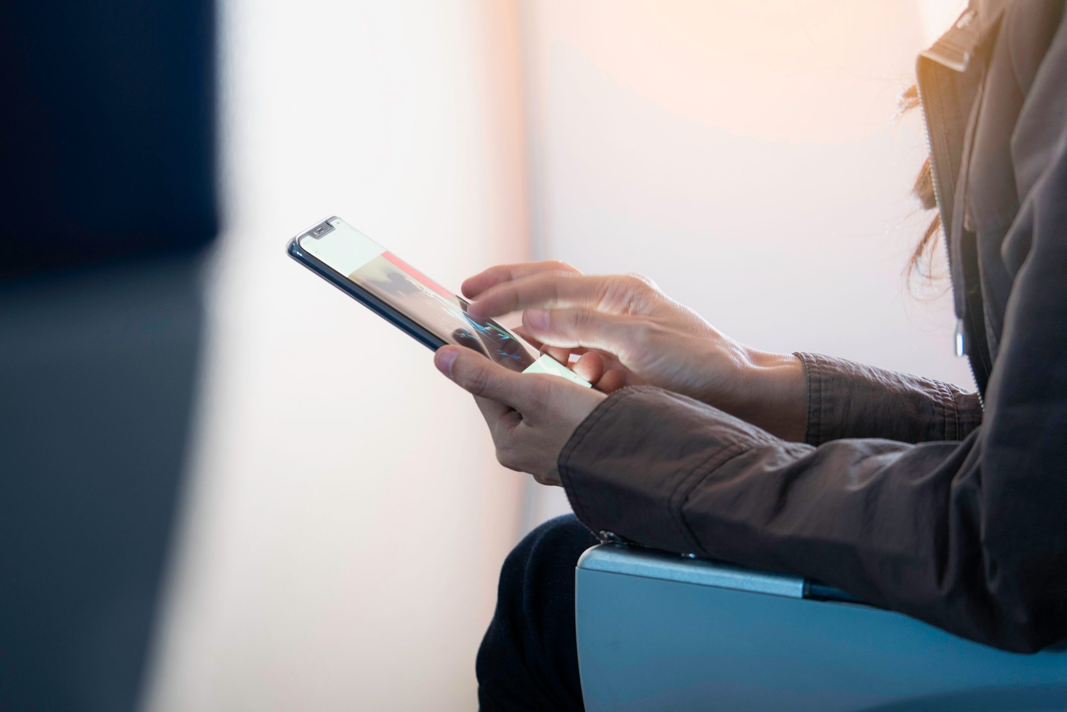 Midsection Of Woman Using Mobile Phone While Sitting In Airplane