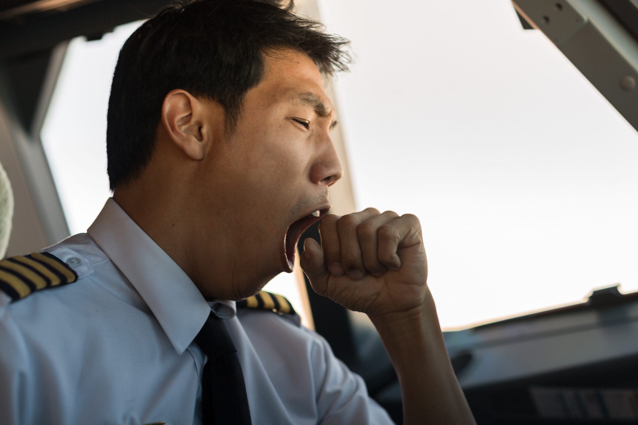 Tired man yawning at work. Pilot flying airplane.