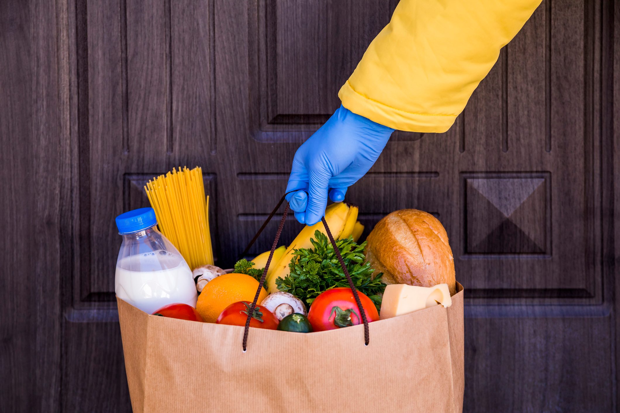 Contactless food delivery. Paper bag with food in the hands of a courier.