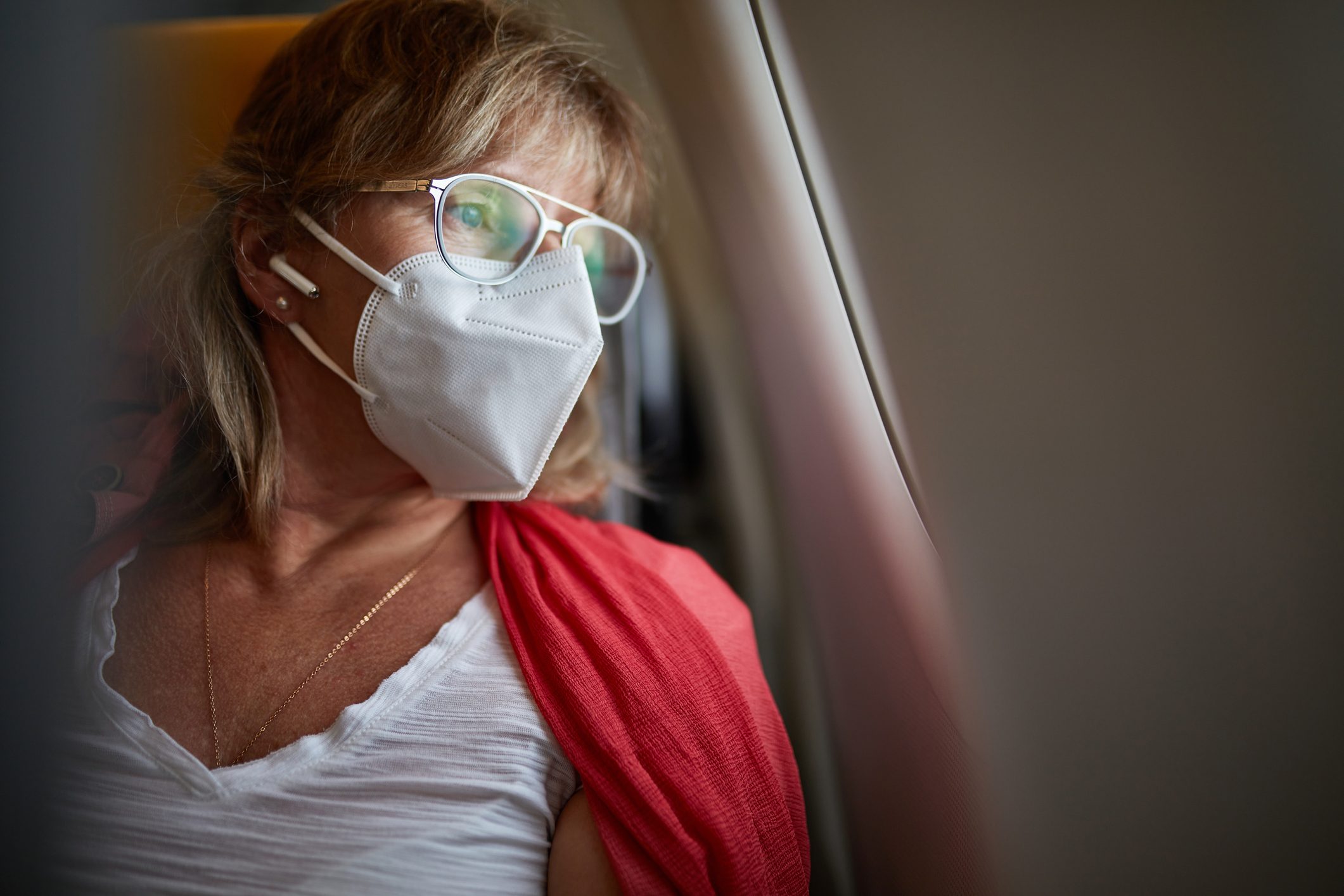 Female Traveler in KN95 Mask Looking Out Airplane Window