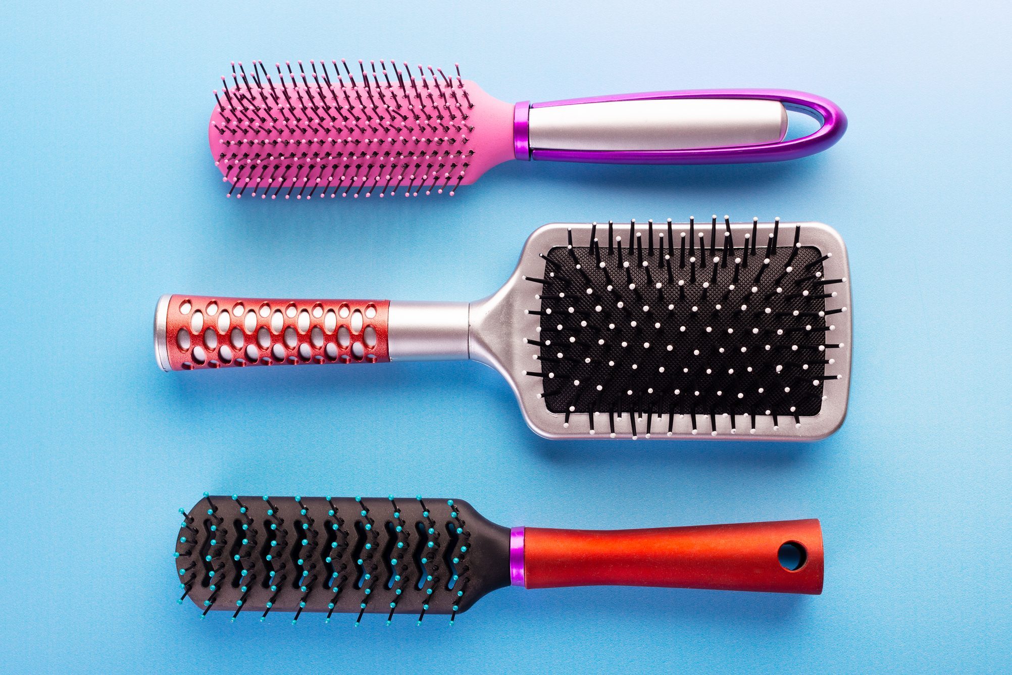 three plastic hairbrushes on blue background