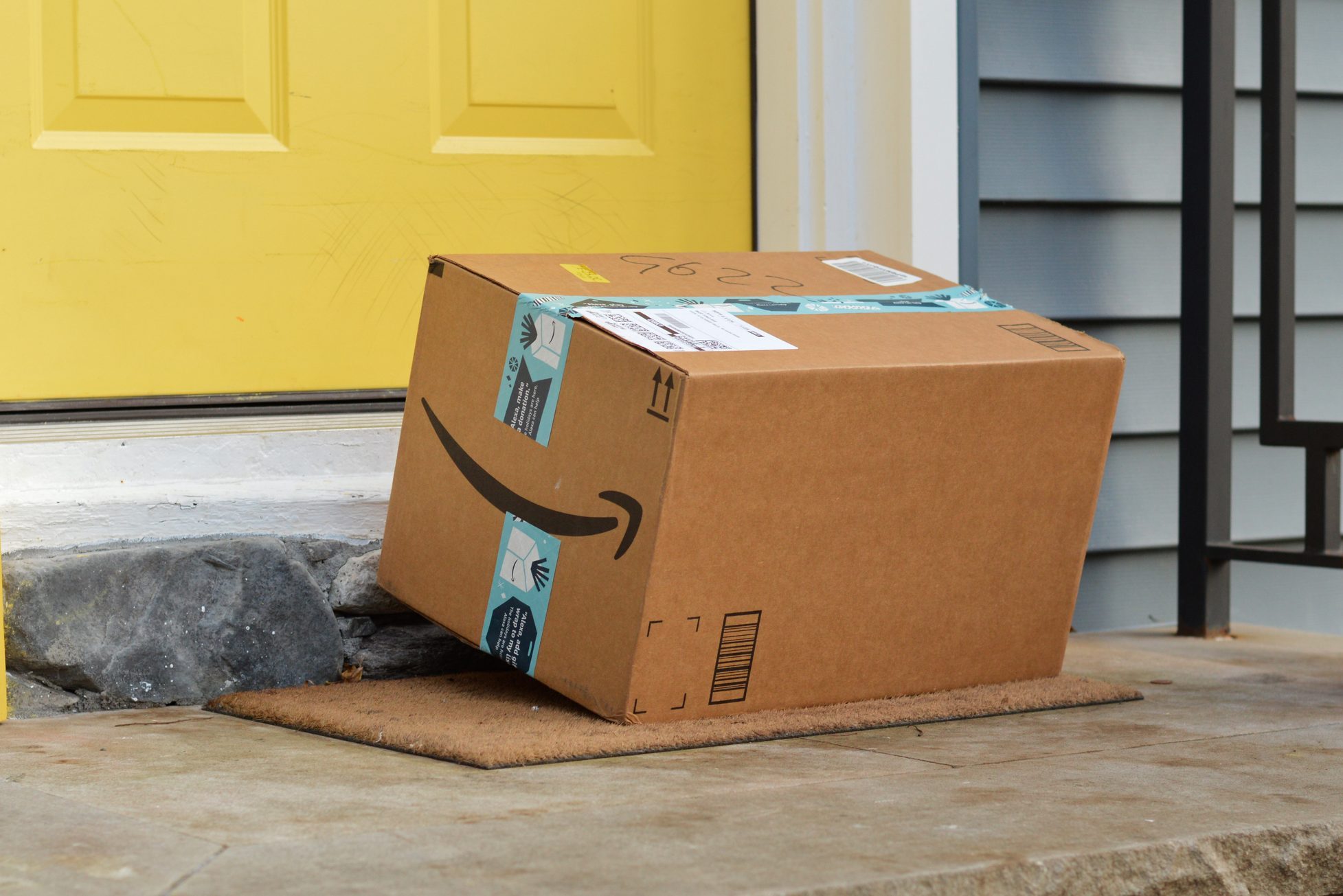 amazon box sitting on a front step near a yellow front door