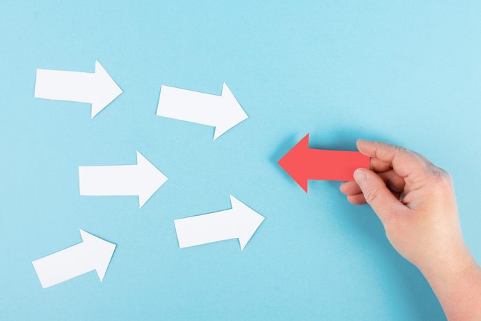 person holding a red arrow and changing direction with multiple white arrows coming towards it