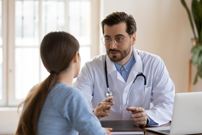 Serious Caucasian male doctor in white medical uniform talk discuss results or symptoms with female patient, man GP or physician consult woman client give recommendation at meeting in hospital