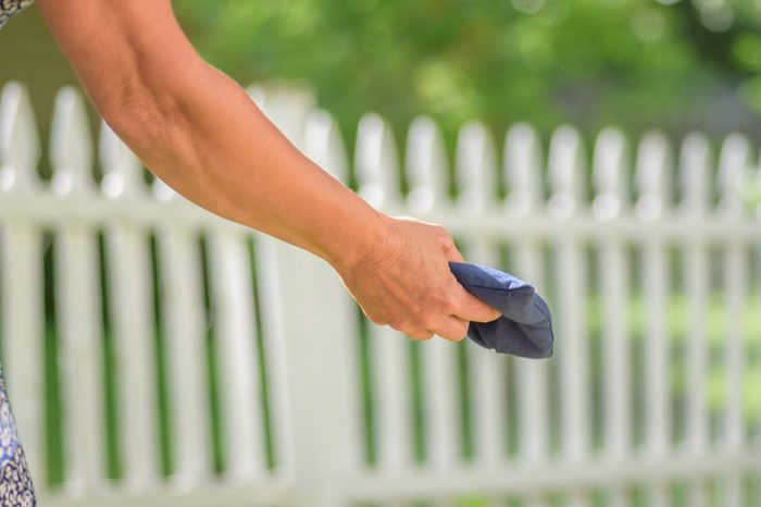 Woman playing bean bag toss game in backyard