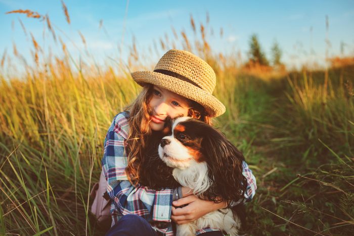 young girl hugging her cavalier king charles spaniel