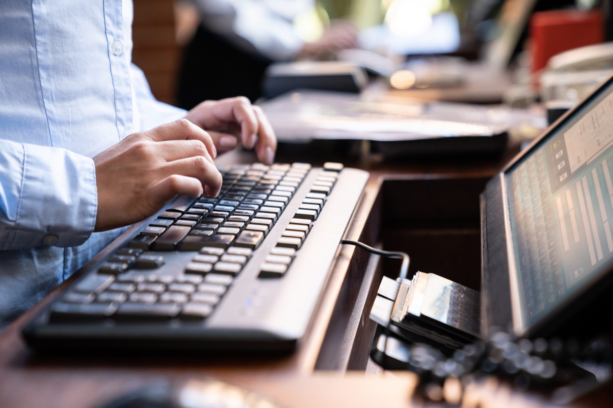 Unrecognizable female hotel receptionist working on computer