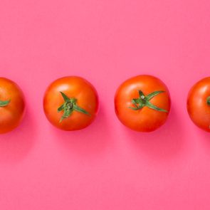 four red tomatoes on a pink background