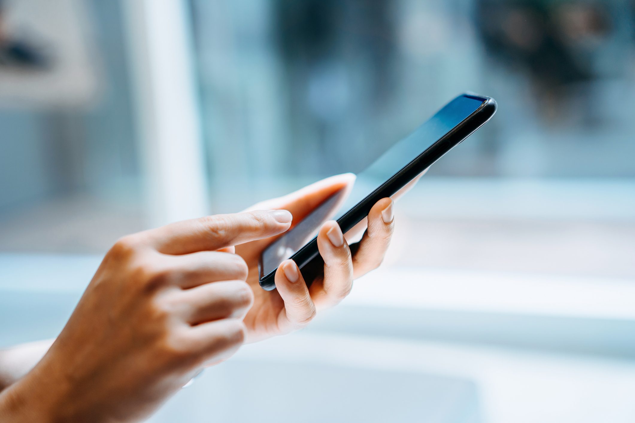 Close up of young woman using smartphone at home in sunlight