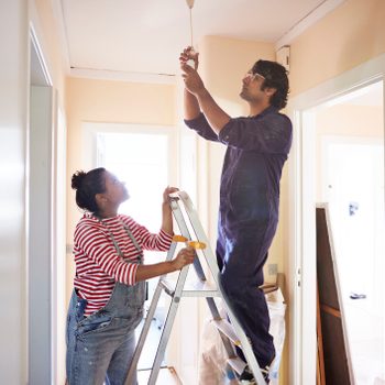 Couple changing light bulb in corridor