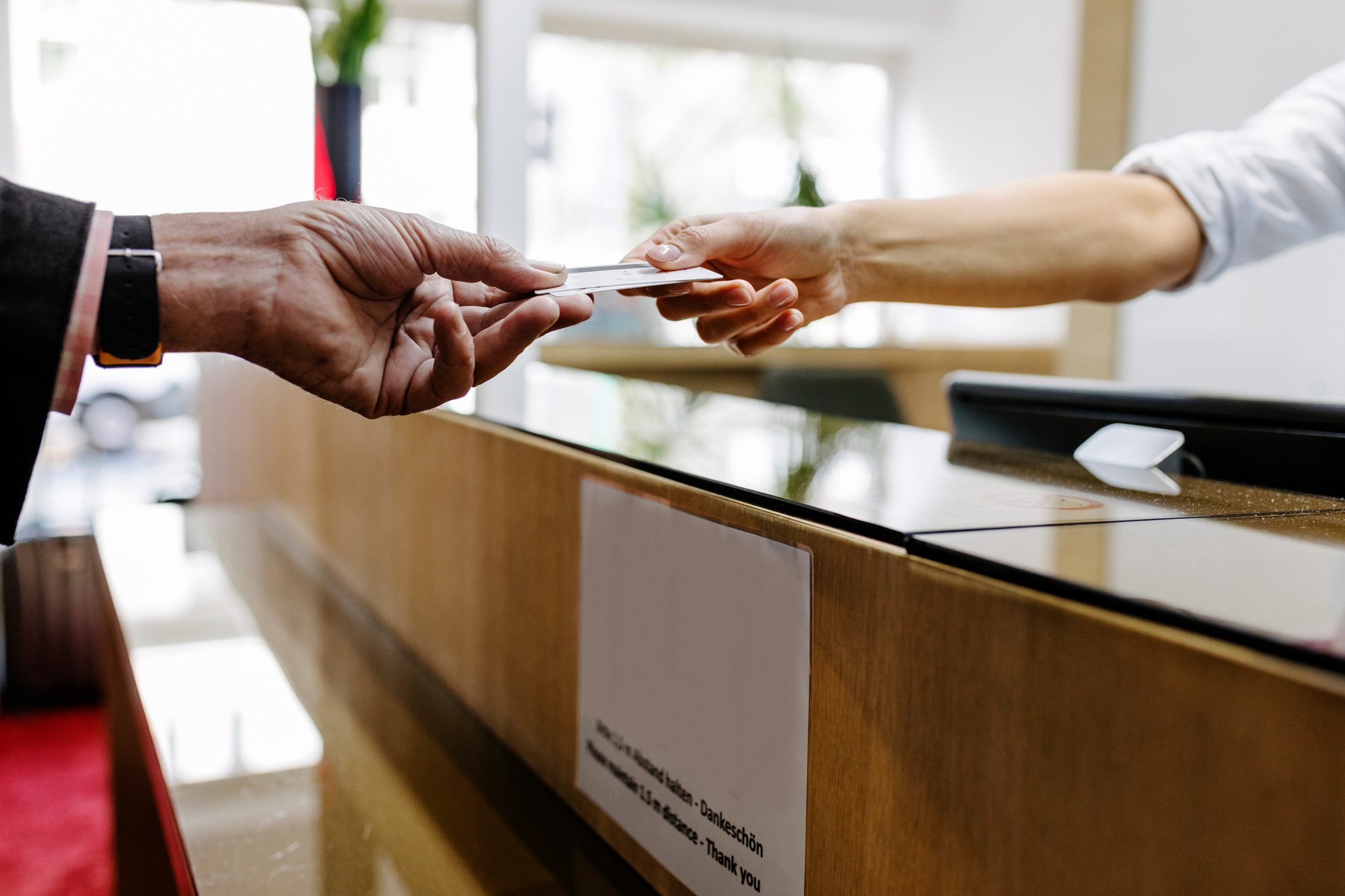 Customer Handing Credit Card To Receptionist From A Distance