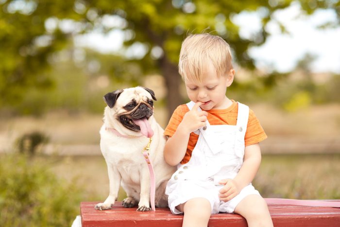 Cute baby boy sitting with pug