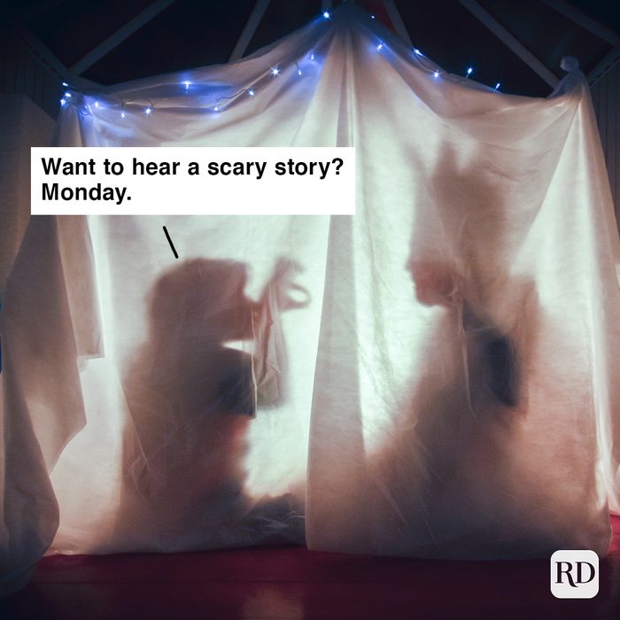 A parent and child tell each other stories inside a cosy tent lit up in a dark room of their home