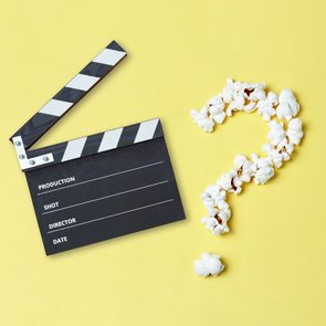 Open Hollywood clapperboard next to popcorn in the shape of a question mark