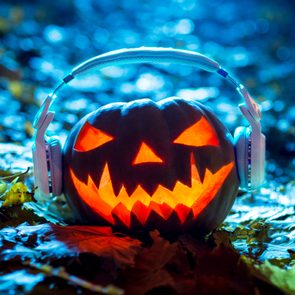 lit jack-o-lantern wearing headphones listening to halloween music