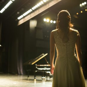 female Pianist walking towards a piano on stage