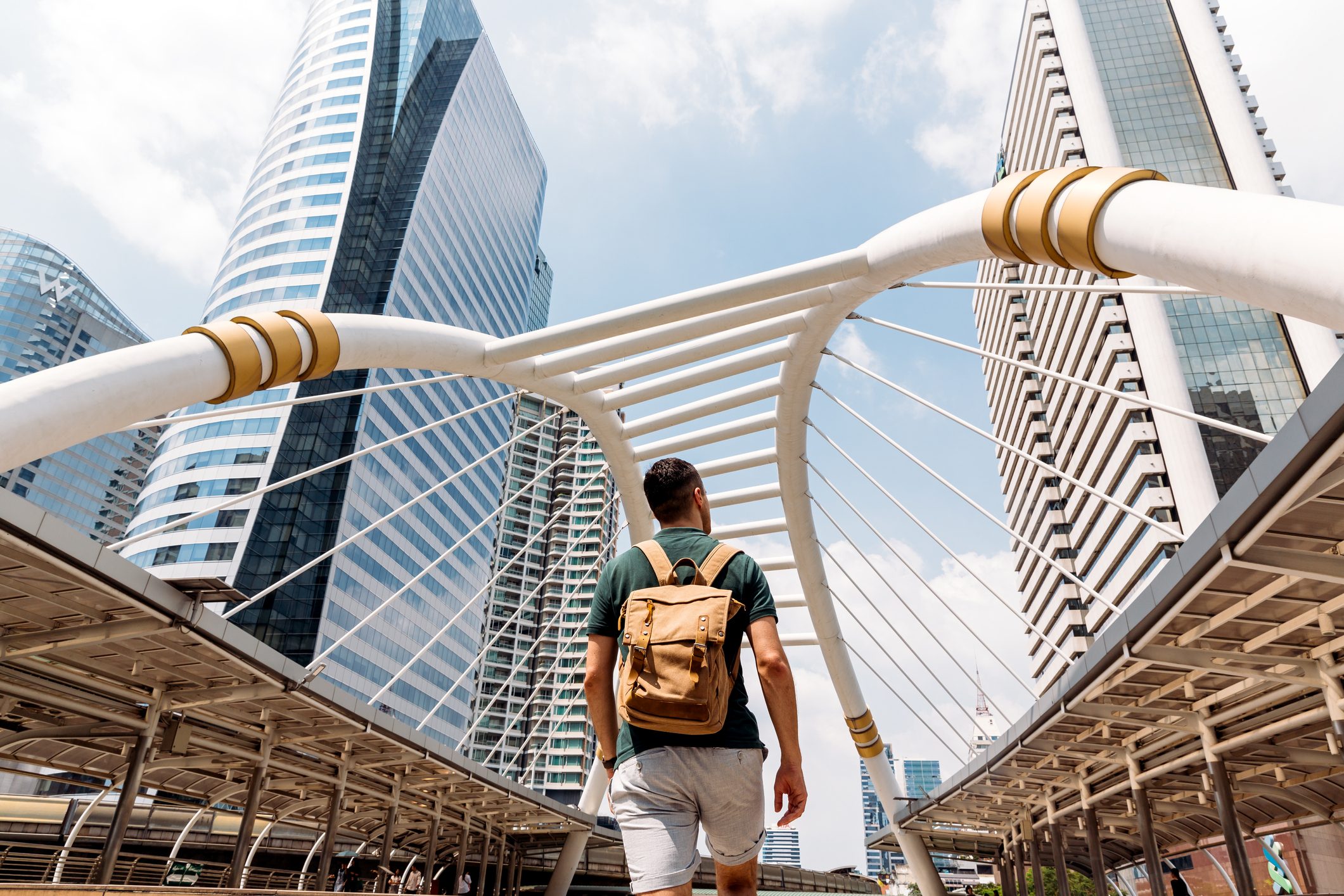 Rear view of a man with backpack admiring modern skyscrapers in Bangkok, Thailand