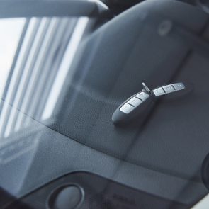 Automobile keys lying on the front dashboard of the car; captured through the window
