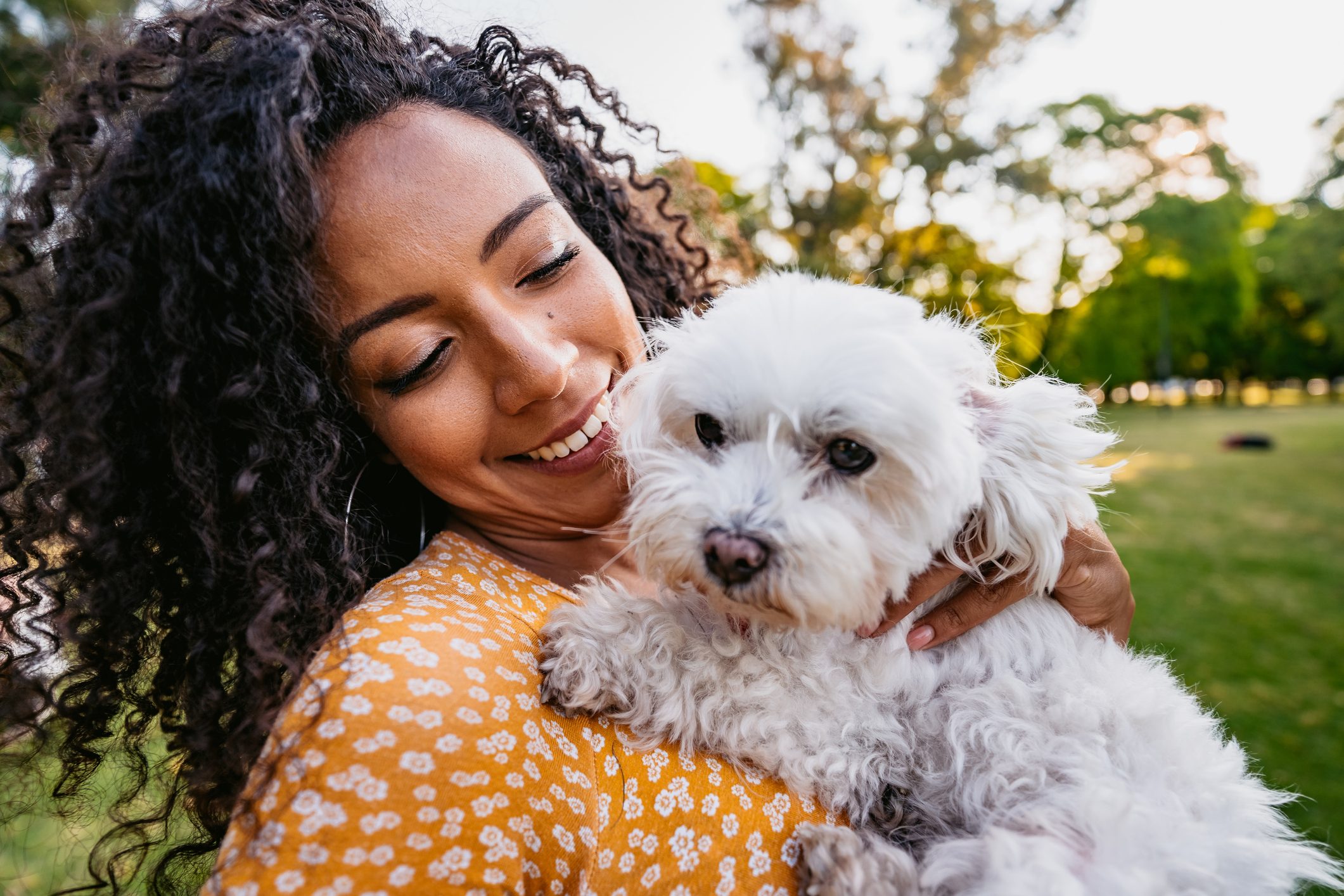 young woman holding her maltese dog in the park