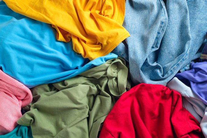 Lots of bright dirty colorful scattered clothes, abstract background. The concept of homework, lack of time for household chores.