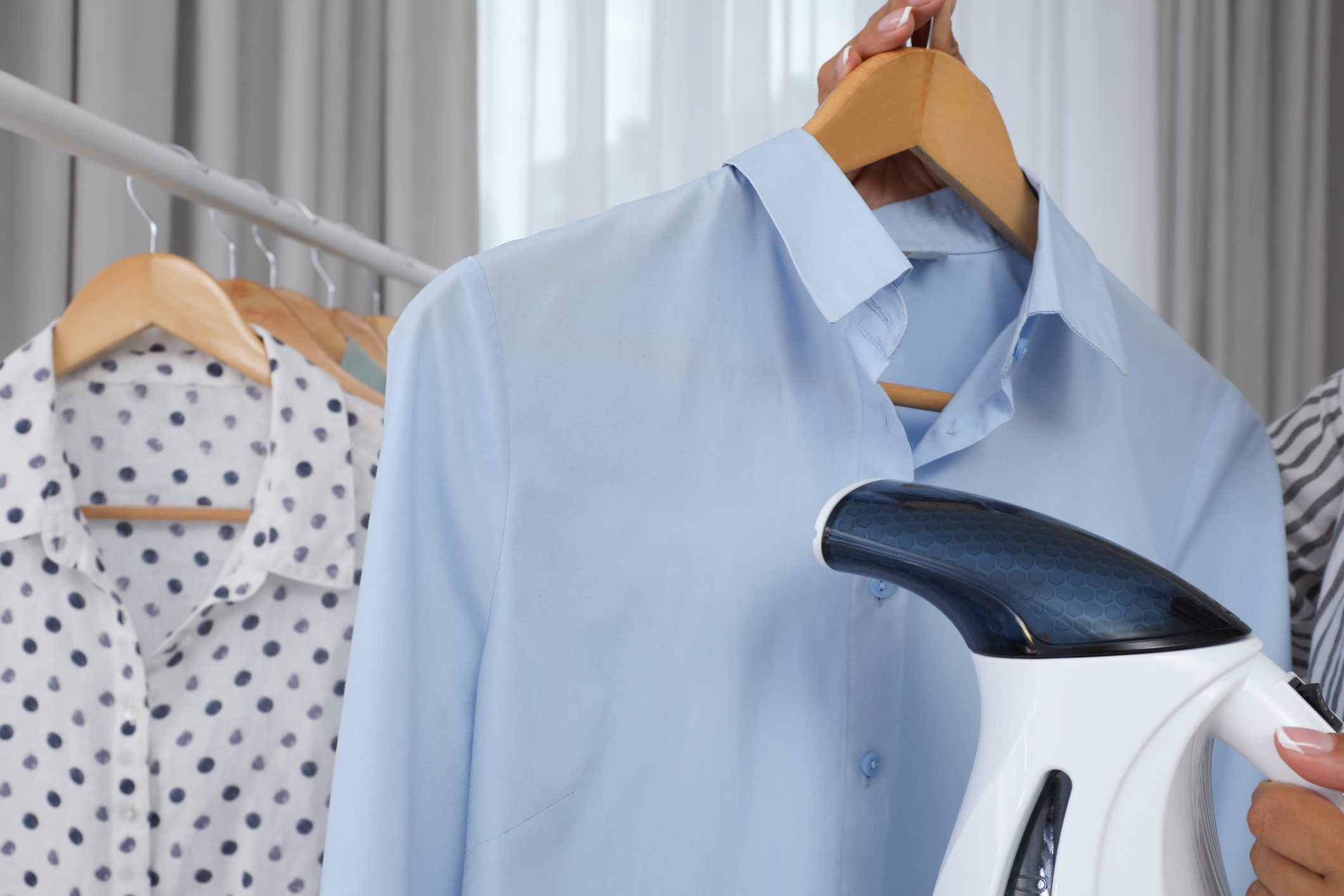 Woman steaming shirt on hanger at home