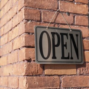 Open sign hanging on a brick wall on a sunny november day; open on thanksgiving