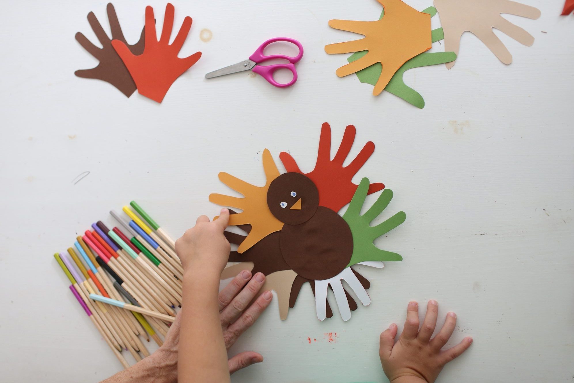 Students and teacher making Thanksgiving turkey crafts in classroom