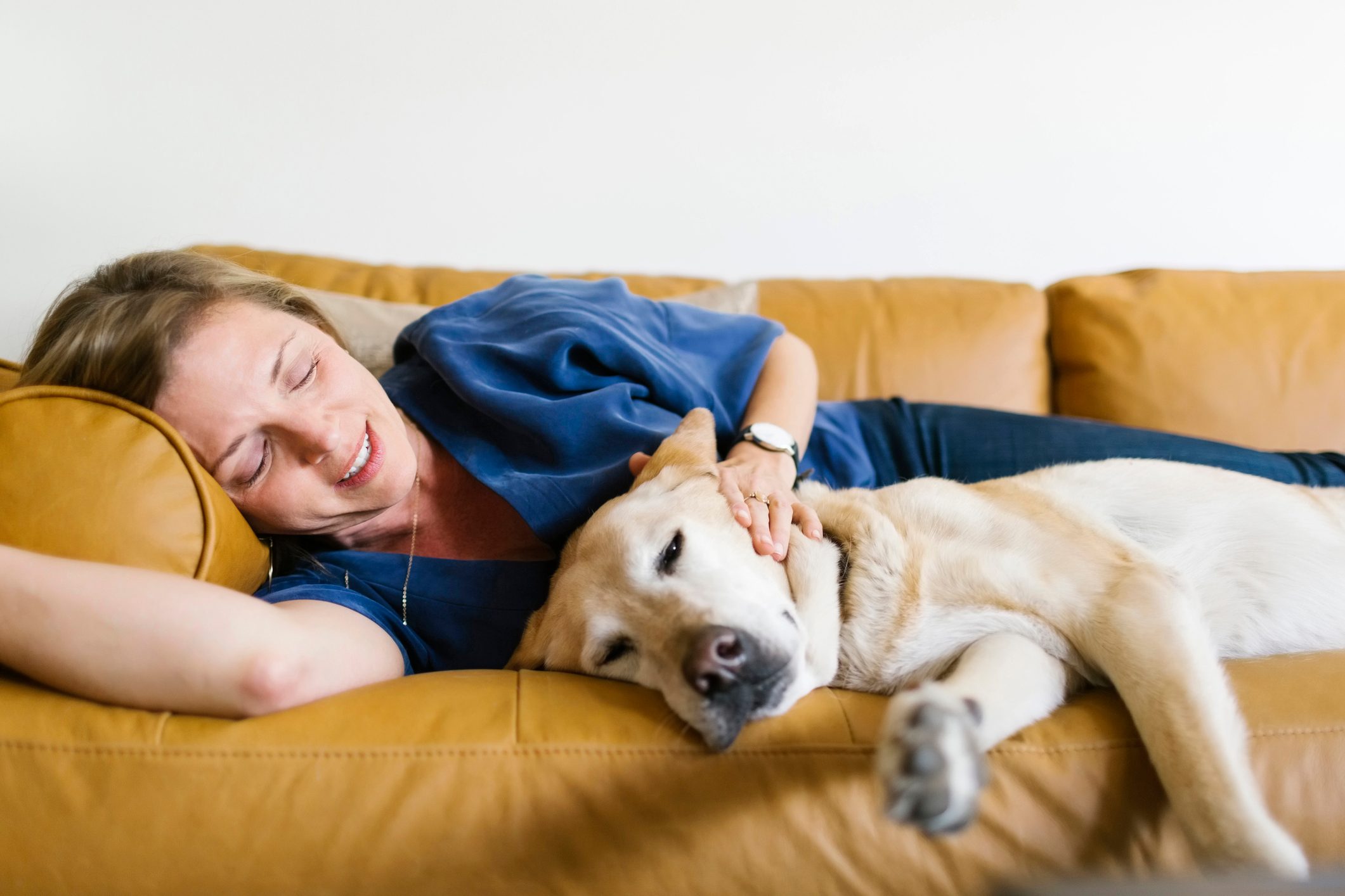 Woman and Labrador Retriever lying down on sofa