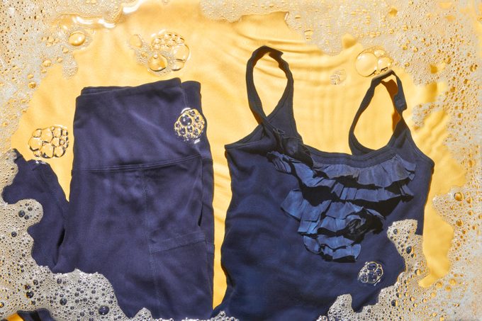 Athletic tights and delicate tank top on yellow background with soap bubbles around