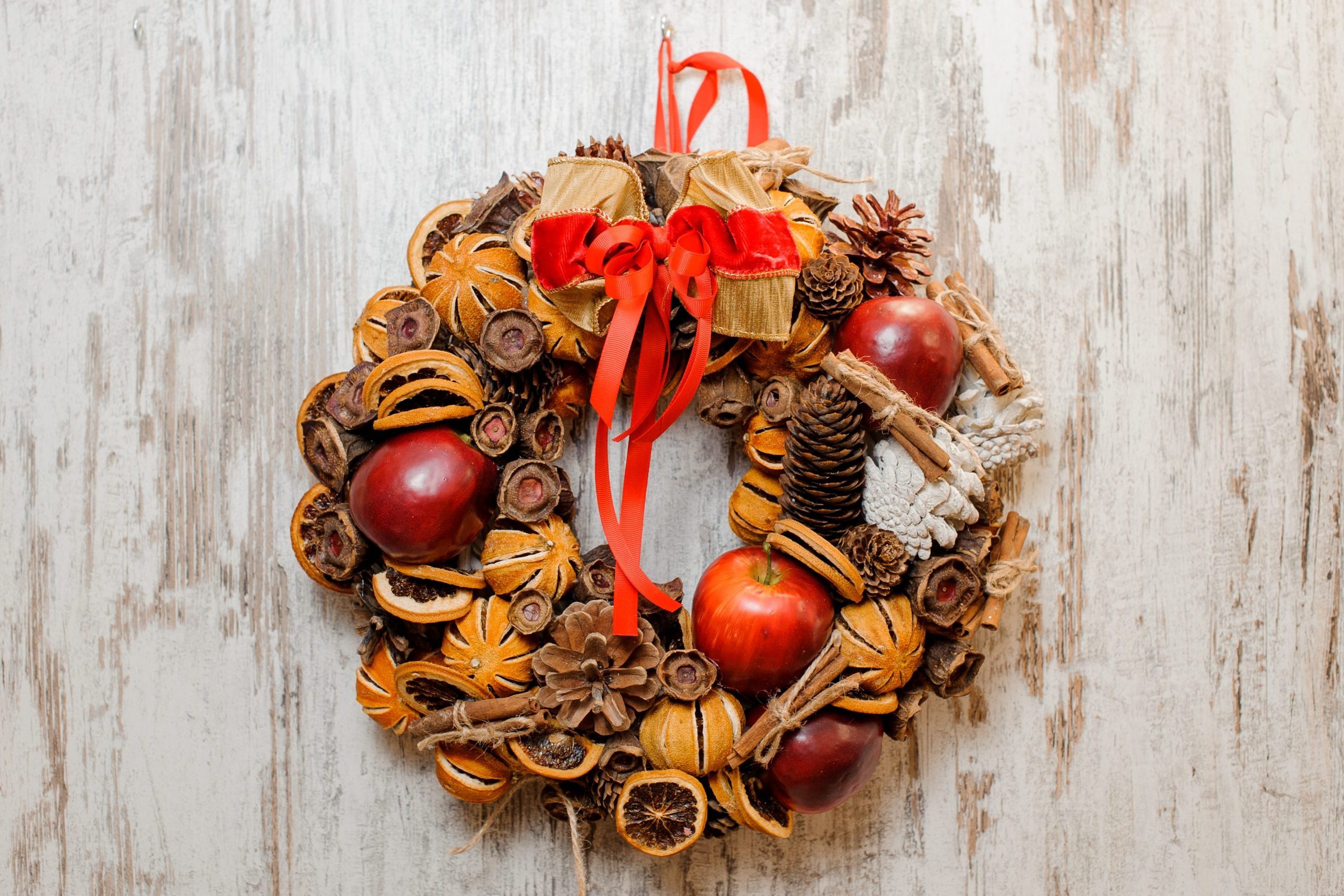 Christmas Wreath decorated with red apples, dried orange slices, cones, cinnamon sticks and bow