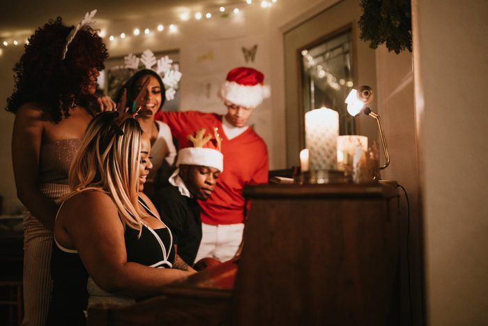 group of friends singing christmas carols around the piano
