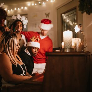 group of friends singing christmas carols around the piano