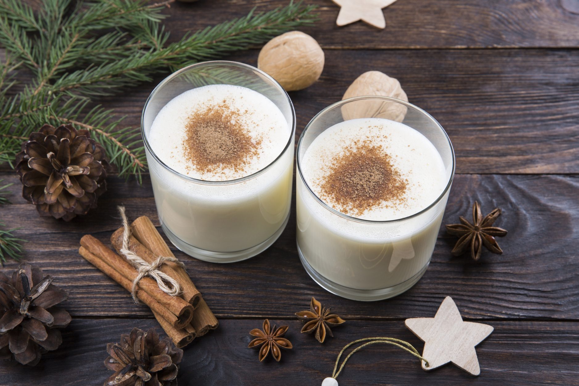 Eggnog with cinnamon in glasses on wooden background, Christmas decor, traditional festive drink.