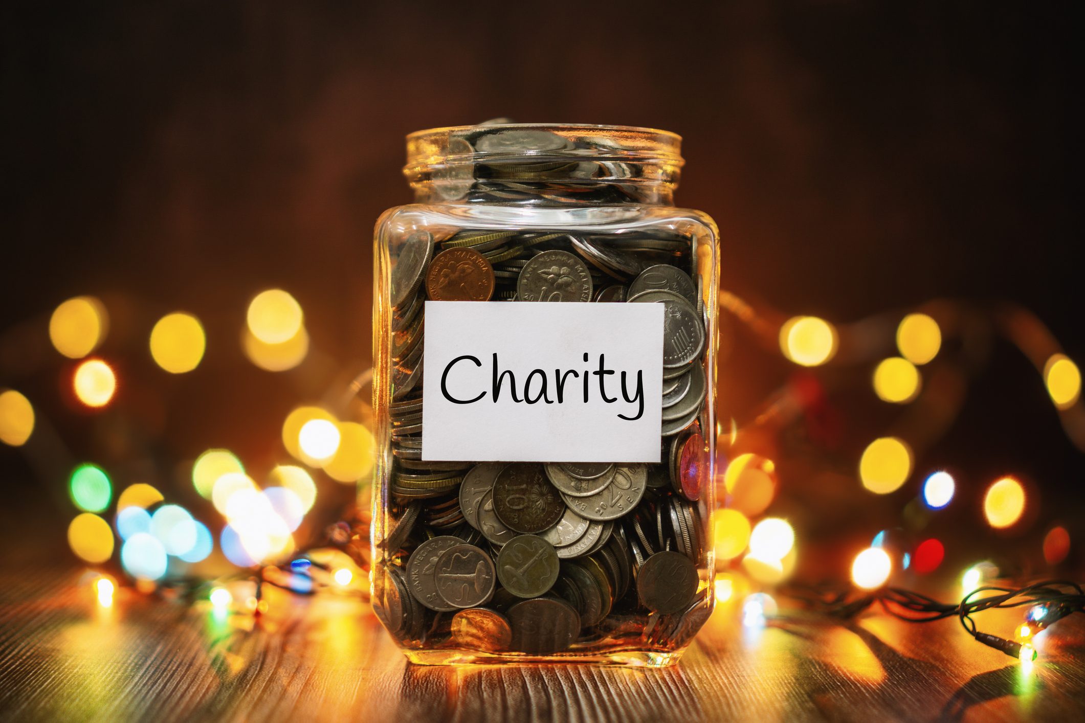 Jar of Coins for Charity Against Christmas Lights Background