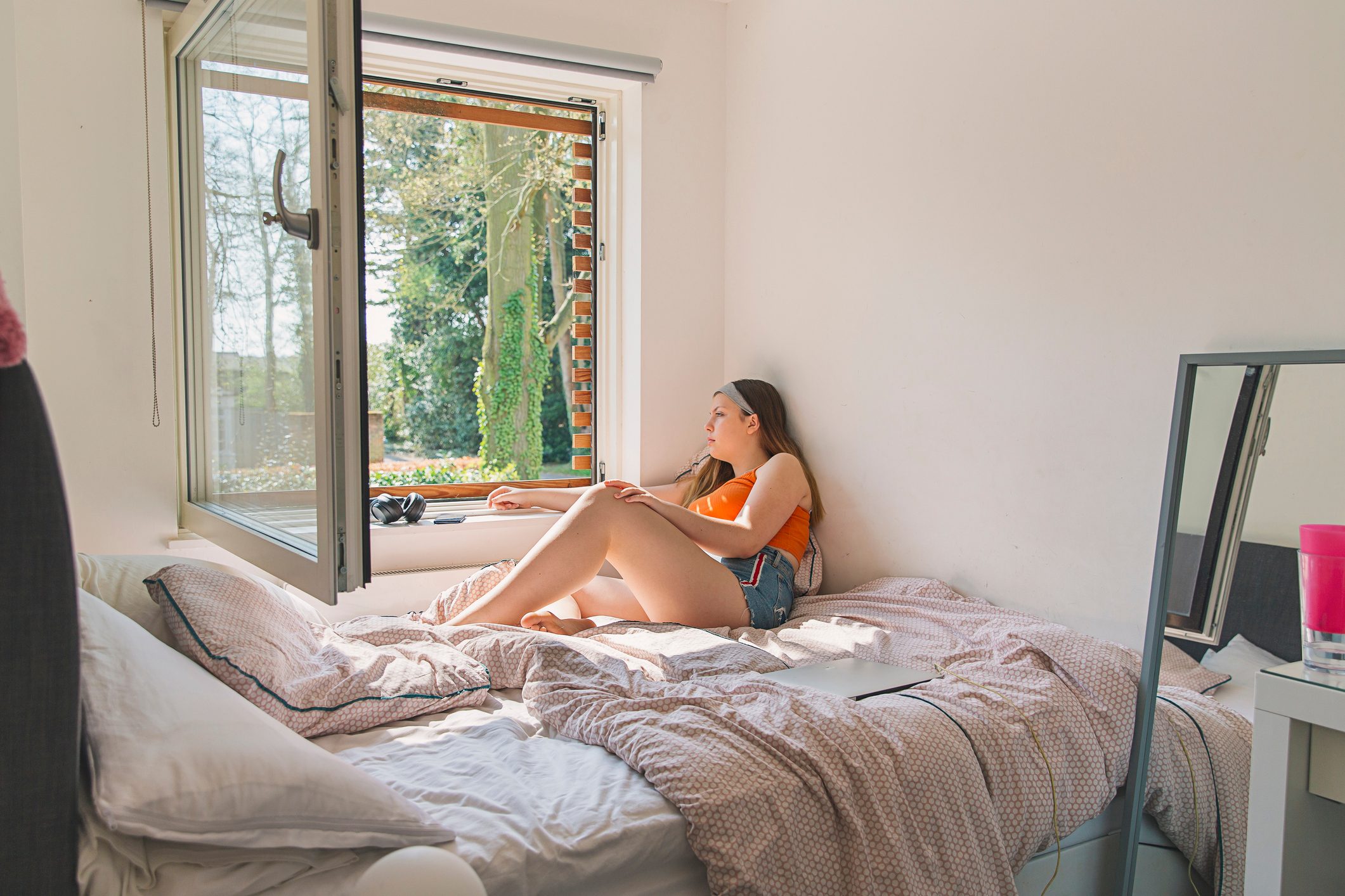 Pensive teenage girl looking out of her window.