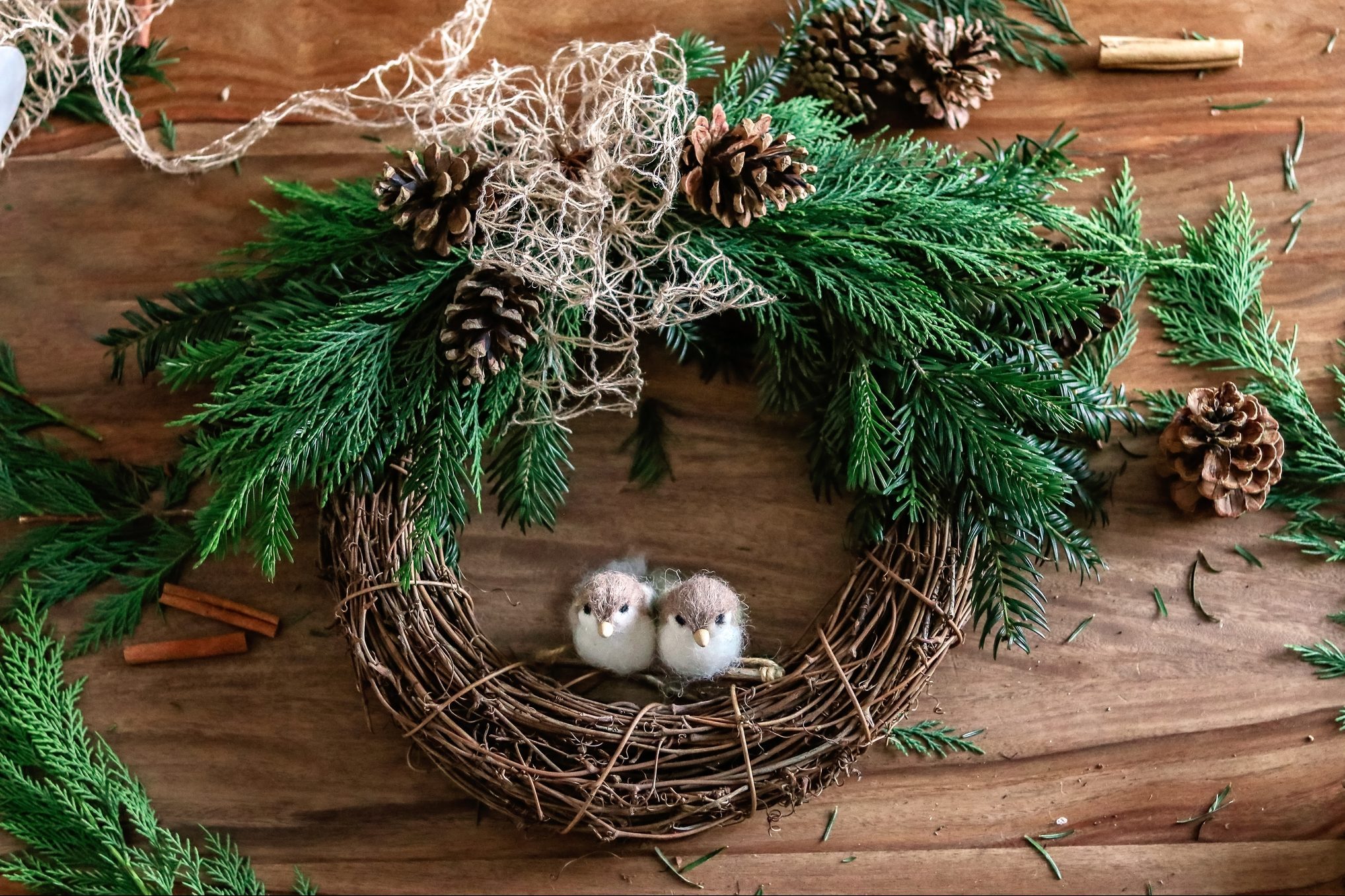 Top view of handmade Christmas wreath made of twigs, pine cones, cinnamon sticks, yew and thuja branches, natural string and wool toys. DIY home decor.