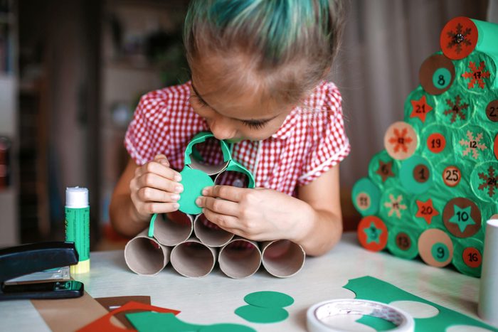 Little girl making Christmas Tree Calendar out of toilet paper rolls