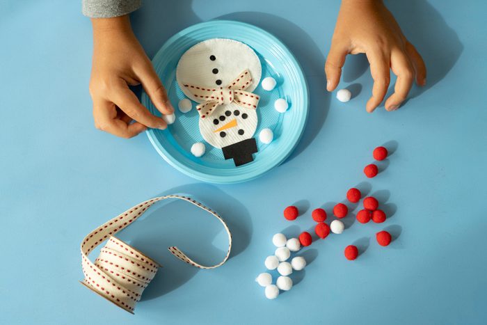 Overhead view of child hands creating a snowman toy at Christmas
