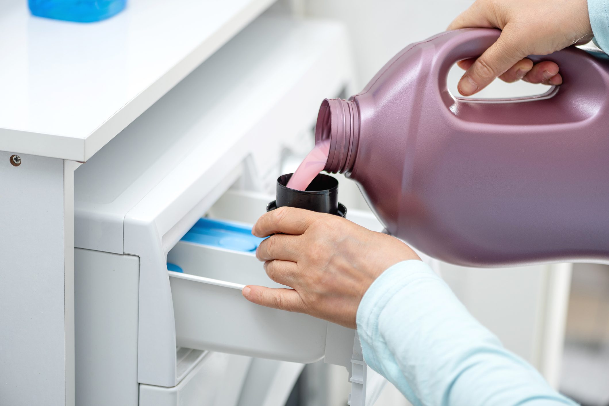 Woman is holding liquid washing machine detergent.