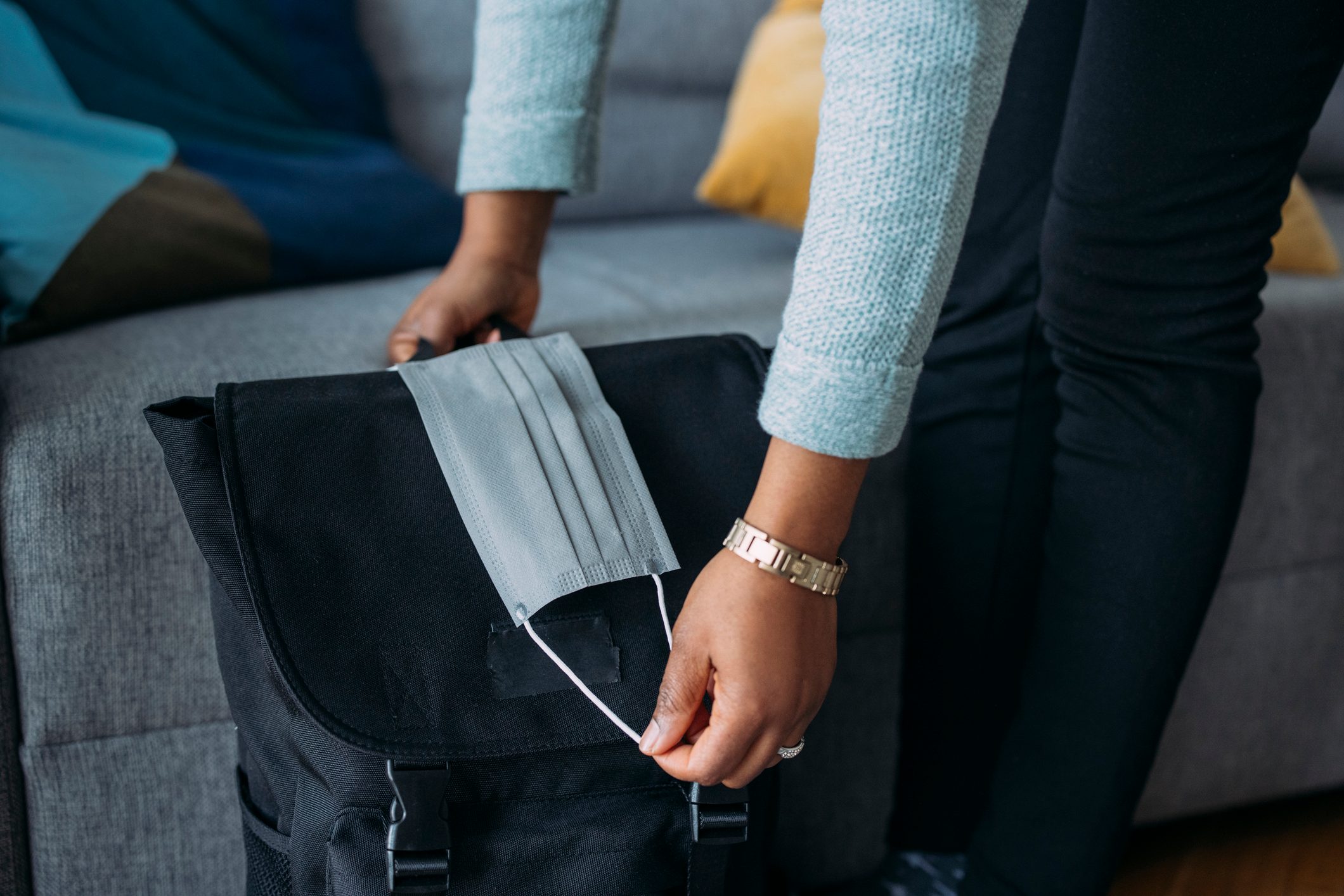 Anonymous Female Packing Stuff in Backpack and Putting Face Mask on the Backpack