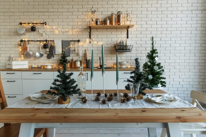 New Year and Christmas. Festive kitchen in Christmas decorations. Candles, spruce branches, wooden stands, table laying.